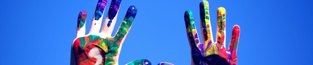 pexels-photo-1428171-1428171 Colorful painted hands raised against a clear blue sky, symbolizing creativity and diversity.