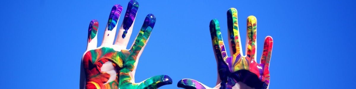 pexels-photo-1428171-1428171 Colorful painted hands raised against a clear blue sky, symbolizing creativity and diversity.